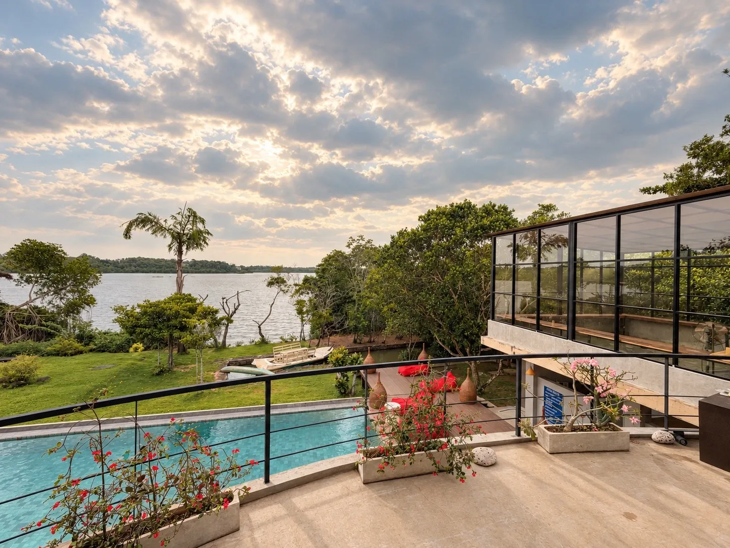 From an upper terrace: the curved pool below, the lawn and Koggala Lake beyond, under an evening sky
