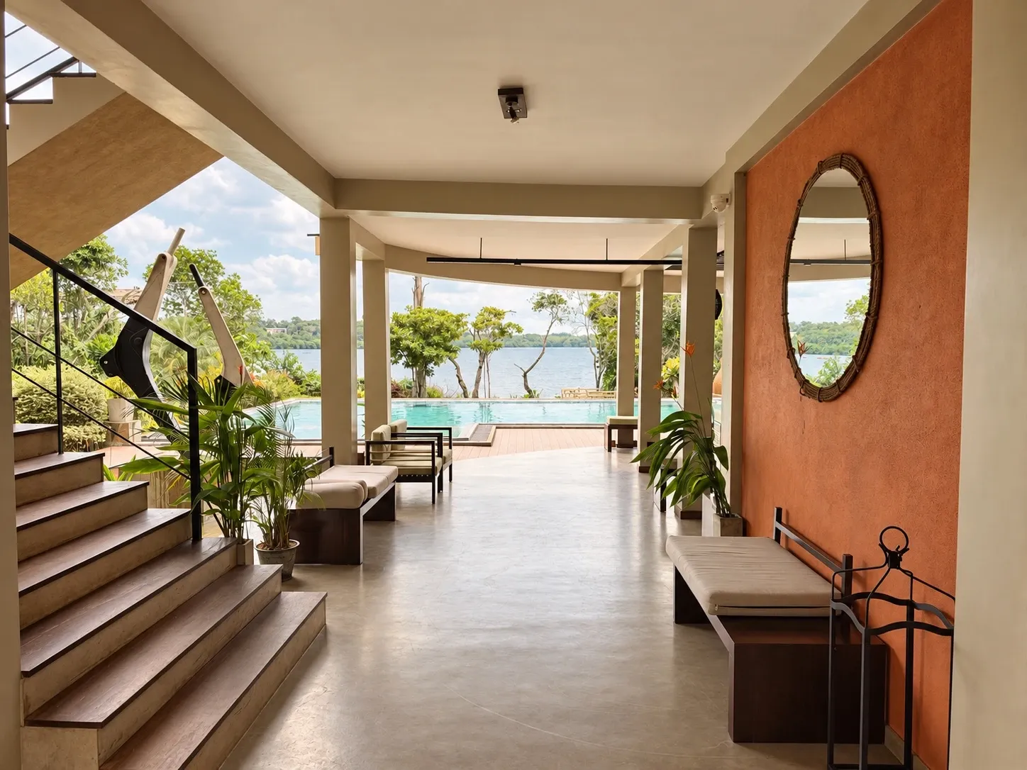 The open lounge: a walkway past an orange wall with a round mirror, out to the pool and the lake