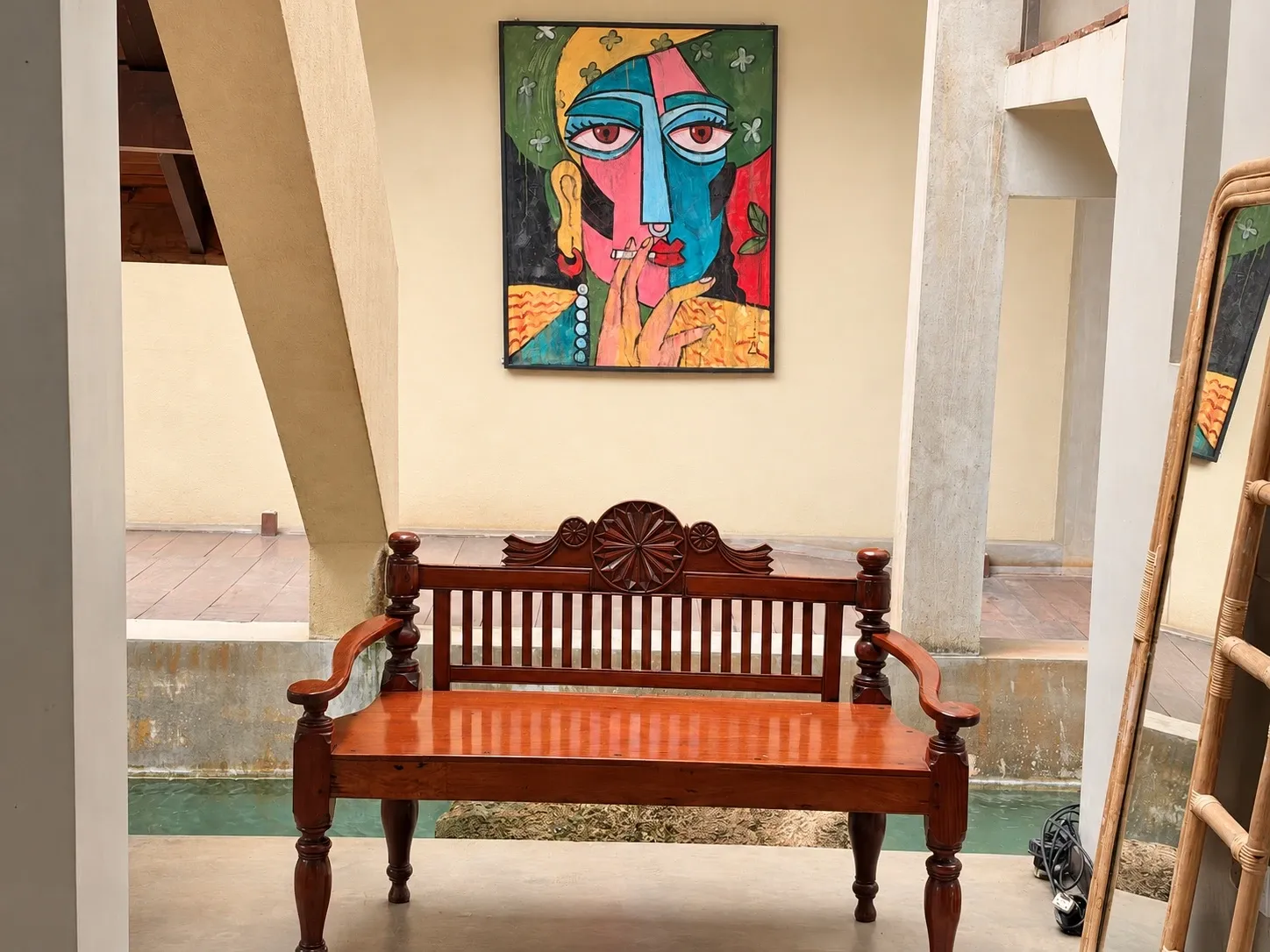 A carved wooden bench beneath a bright portrait painting