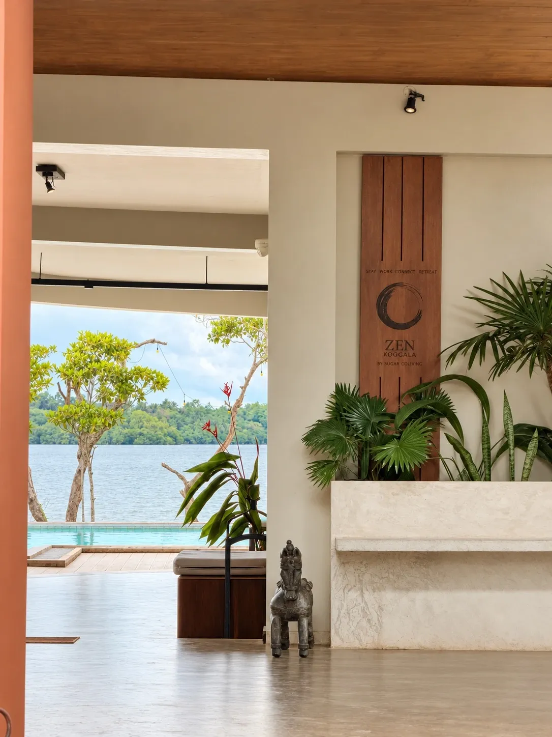 A timber panel with the Zen ensō beside plants, and a view through to the pool and the lake